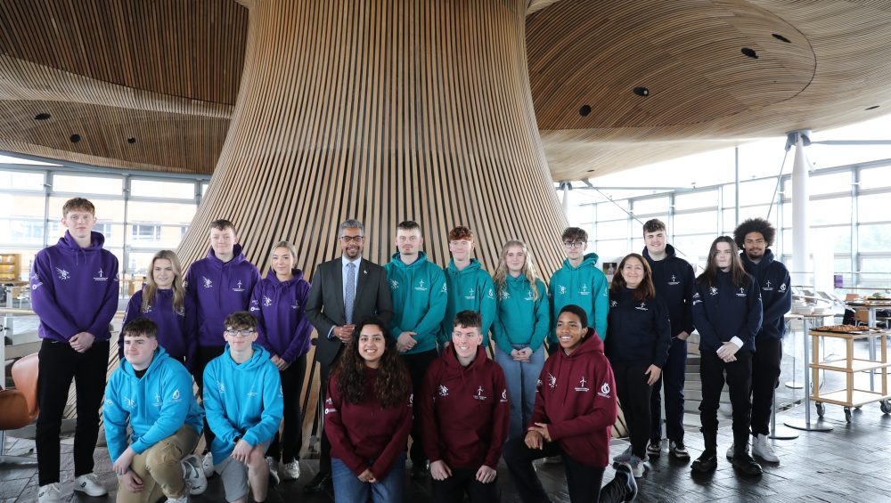 Competitors in the Senedd wearing hoodies and Vaughan Gething is centre