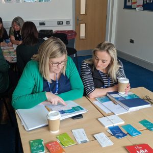 College lectures seated in classroom reading books and leaflets.