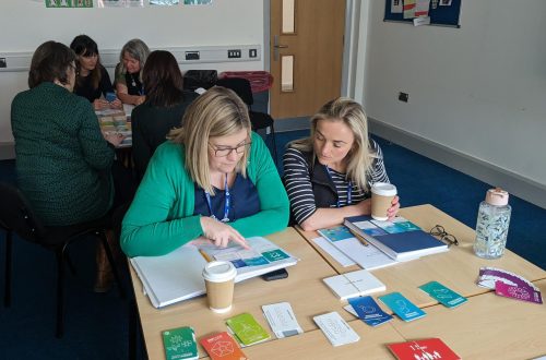College lectures seated in classroom reading books and leaflets.