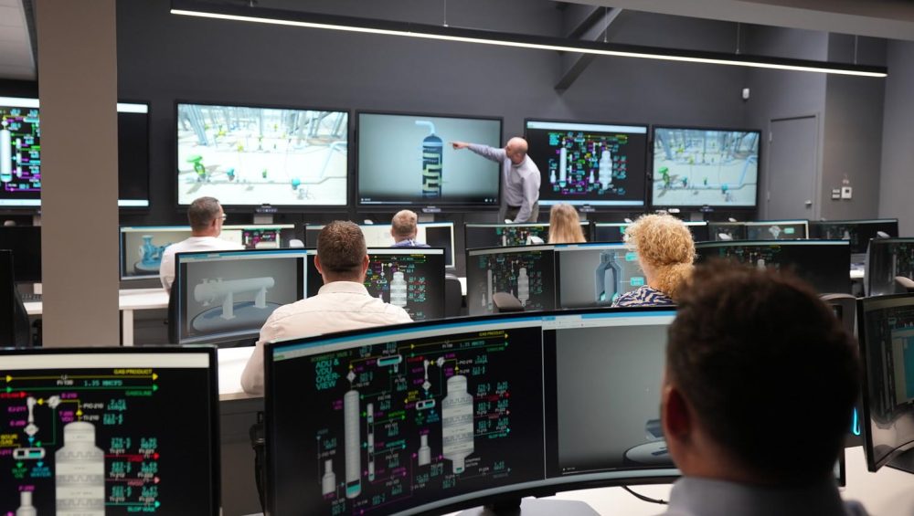 People sitting infant of screens in control room.