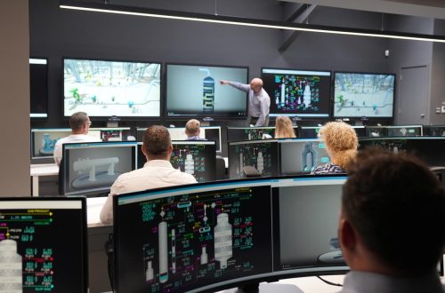 People sitting infant of screens in control room.