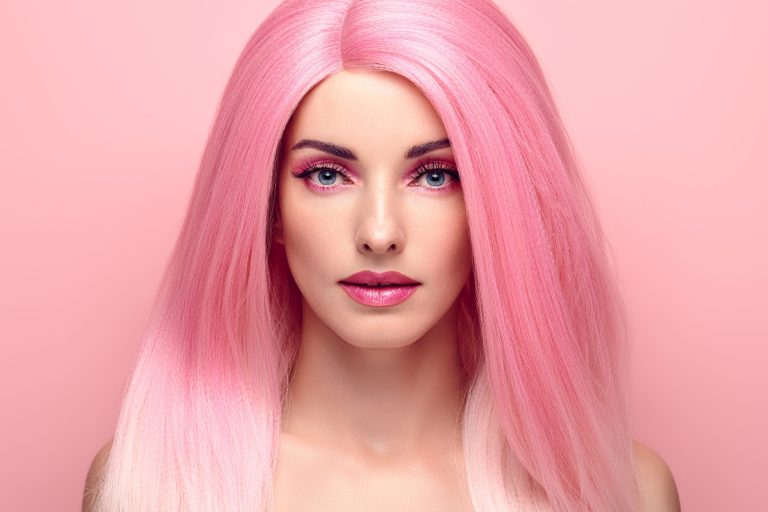 Portrait of a woman with pink hair against a pink background.