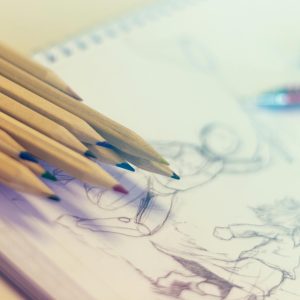 coloured pencils lying on a piece of paper with a drawing on it
