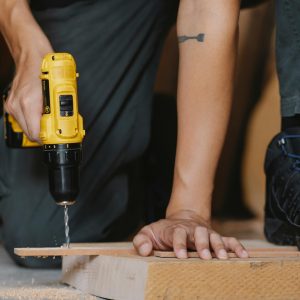 someone kneeling and drilling wood