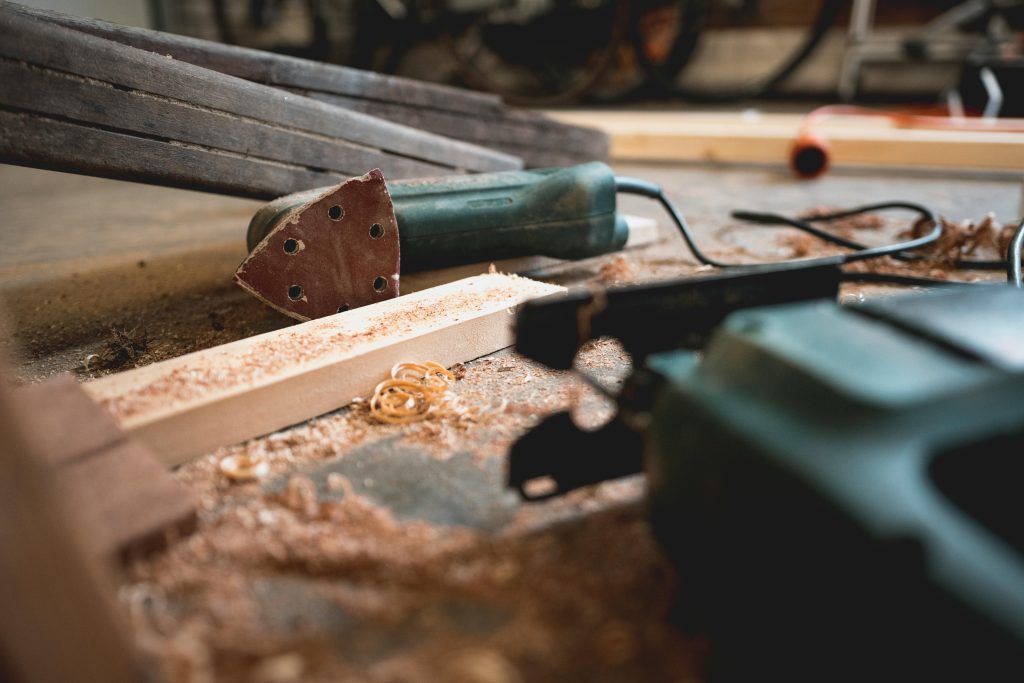 sander lying on it's side along with some wood and shavings