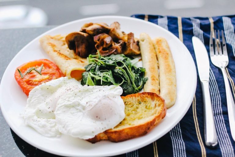 Plate of food with sausages, eggs, mushrooms and tomatoes.