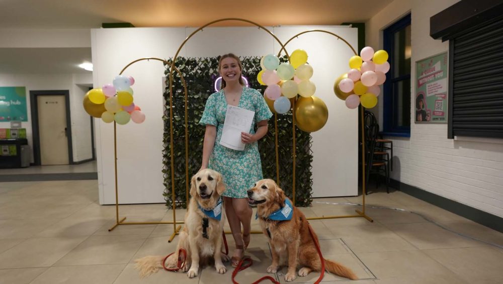 Student holding paper, with two dogs