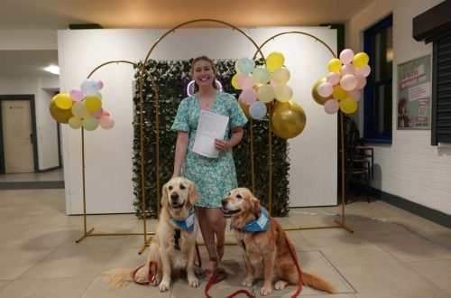 Student holding paper, with two dogs