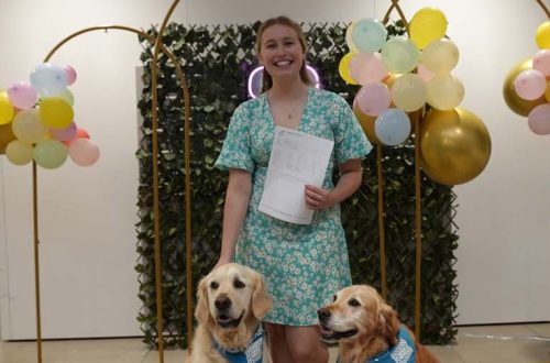 Student holding paper, with two dogs