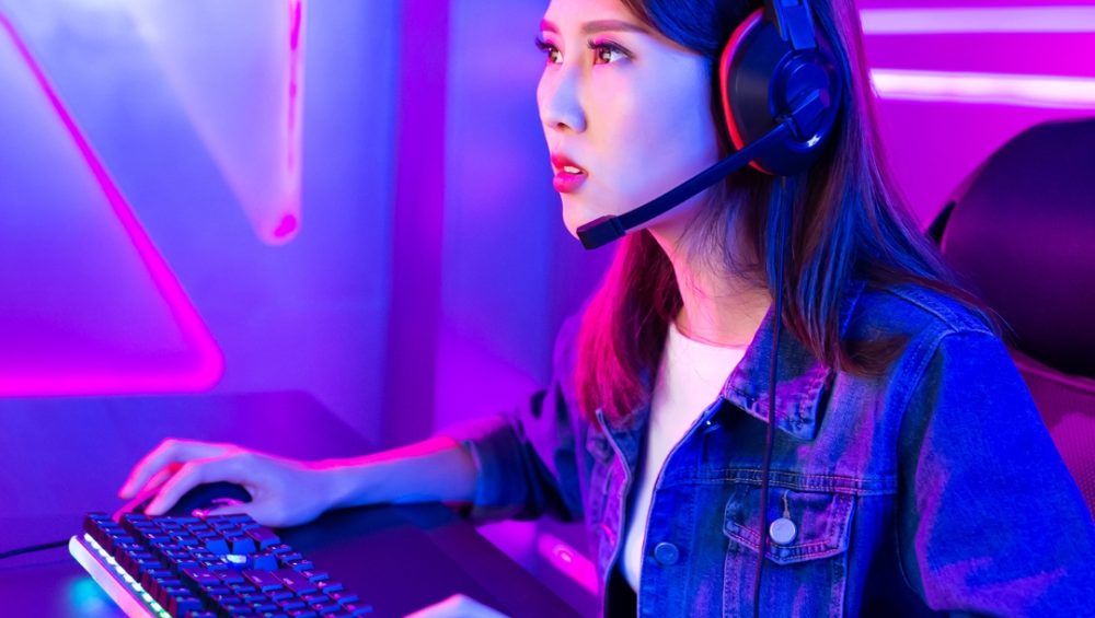 Woman tying on a neon led lit keyboard wearing a head set