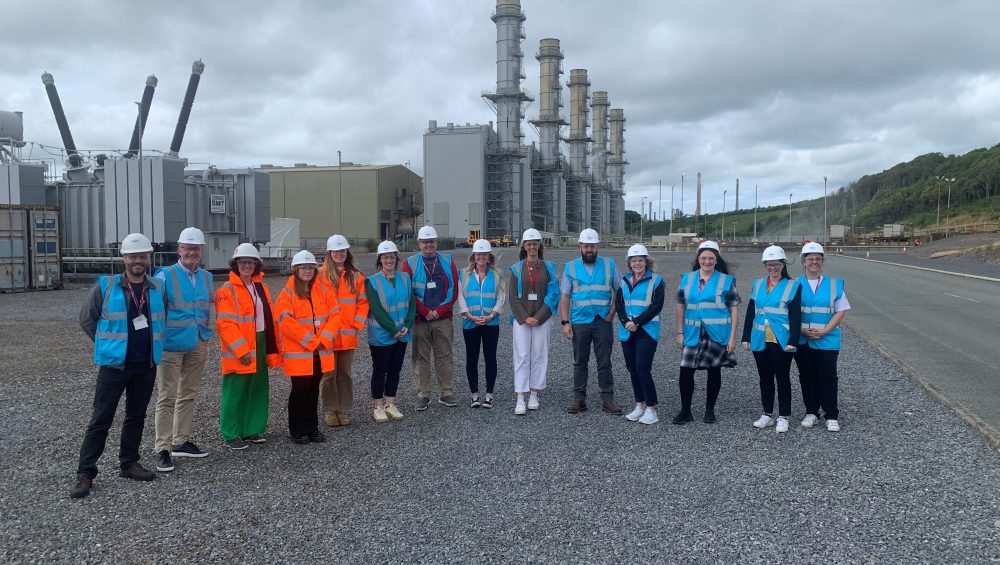Group of staff and students in high viability jackets outside refinery