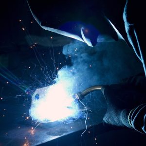 Person wearing a welding mask, welding in the dark