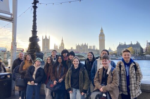 Group of students standing by the Thames with Westminster in background.