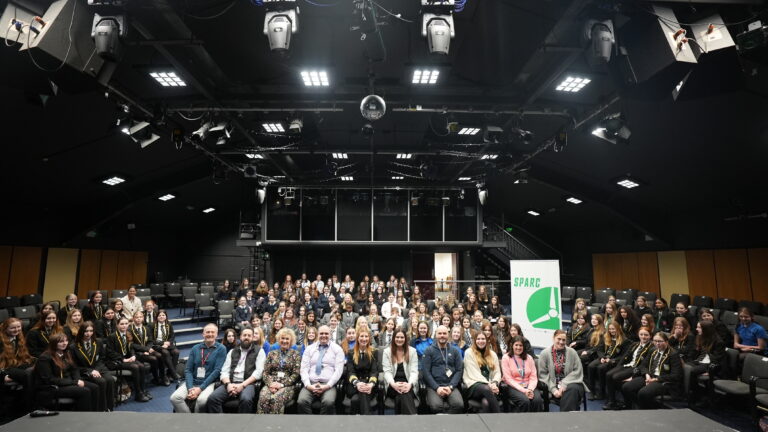 SPARC Alliance including young females and teachers sat in the Merlin Theatre facing the stage