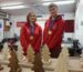Two students wearing red Worldskills hoodies in workshop with wooden trees in foreground