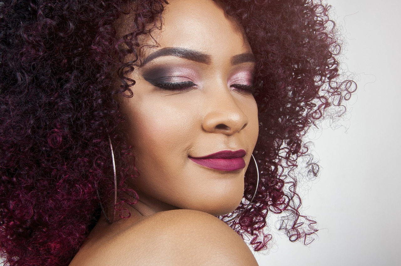 Lady with curly hair, eyes closed with makeup