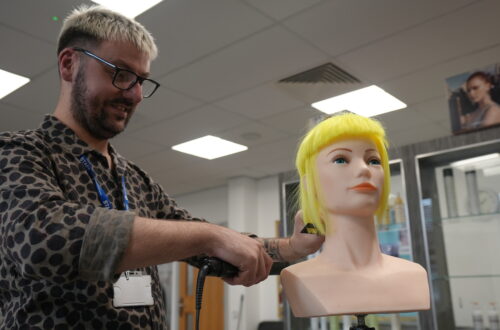 Marcus styling a mannequin head with bright yellow hair