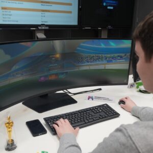 Back of student sitting at wide screen playing Esport game.