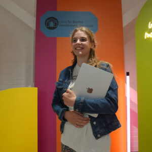 Student holding a laptop against a bright background