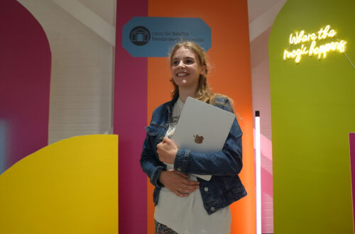 Student holding a laptop against a bright background