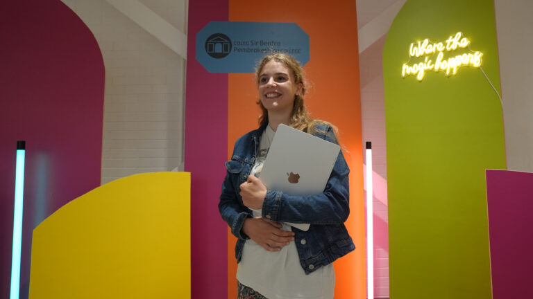 Student holding a laptop against a bright background