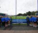 Students and staff stood in front of the Bridge Meadow sign on the Haverfordwest AFC pitch