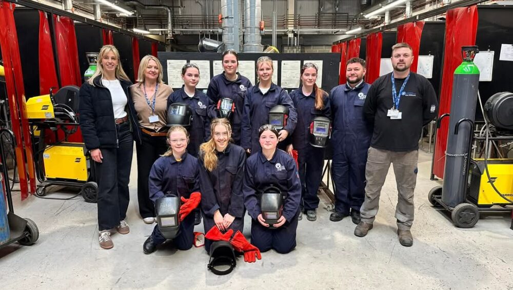 Group photo students and staff in welding workshop.