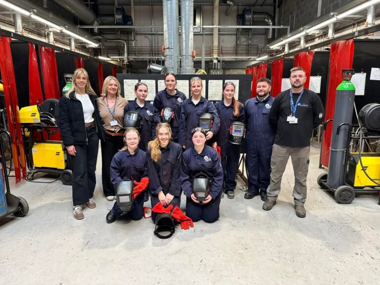 Group photo students and staff in welding workshop.