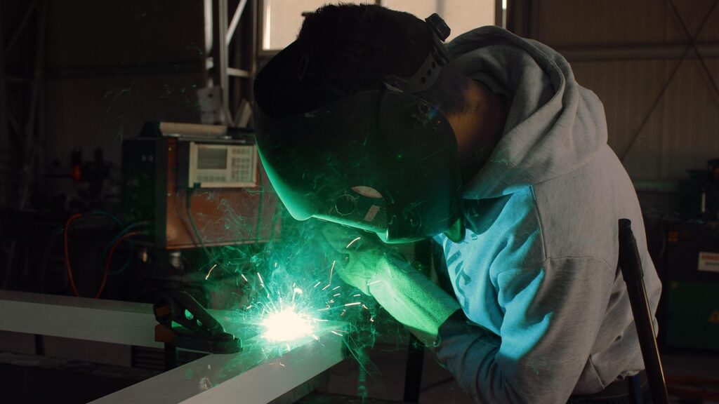 Person in a grey jumper and safety mask, doing welding