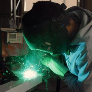 Person in a grey jumper and safety mask, doing welding