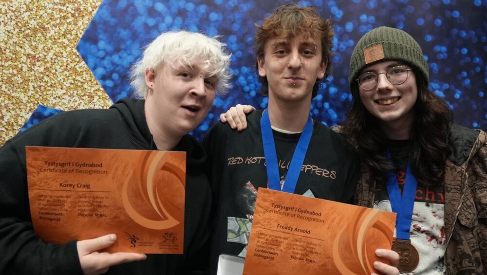 Three people holding certificates and smiling.