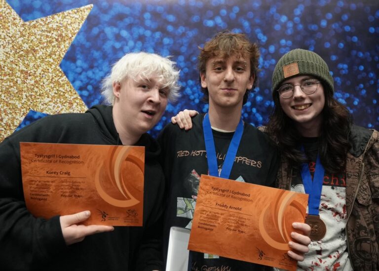 Three people holding certificates and smiling.