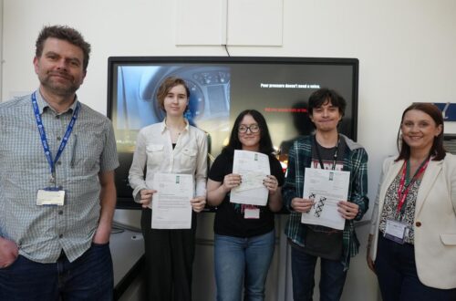 Creative Media lecturer and learners in classroom holding certificates.