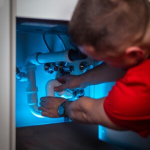 A man working on pipe in a cabinet