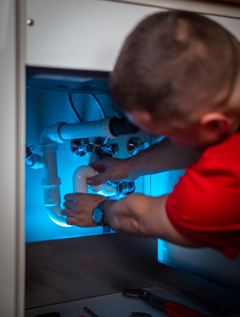 A man working on pipe in a cabinet