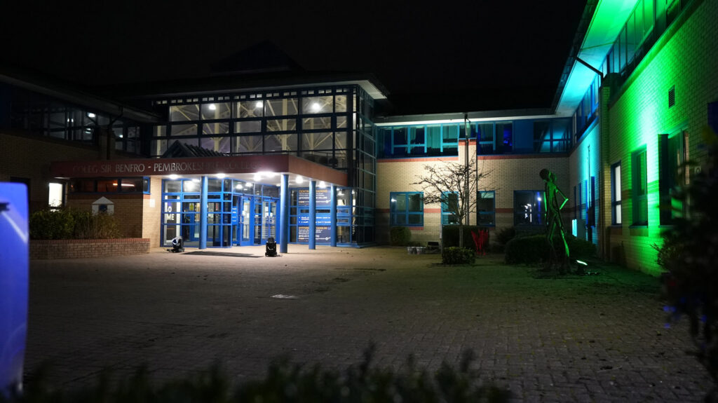 Front of the College at night light up.