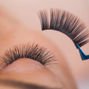 False eyelashes being applied with tweezers.
