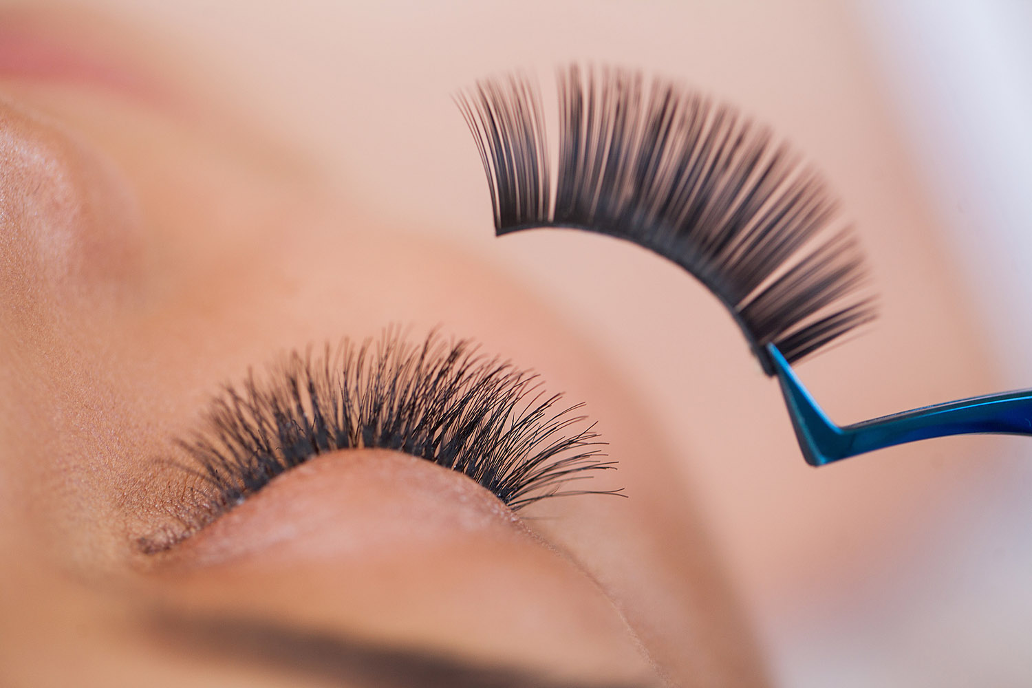 False eyelashes being applied with tweezers.